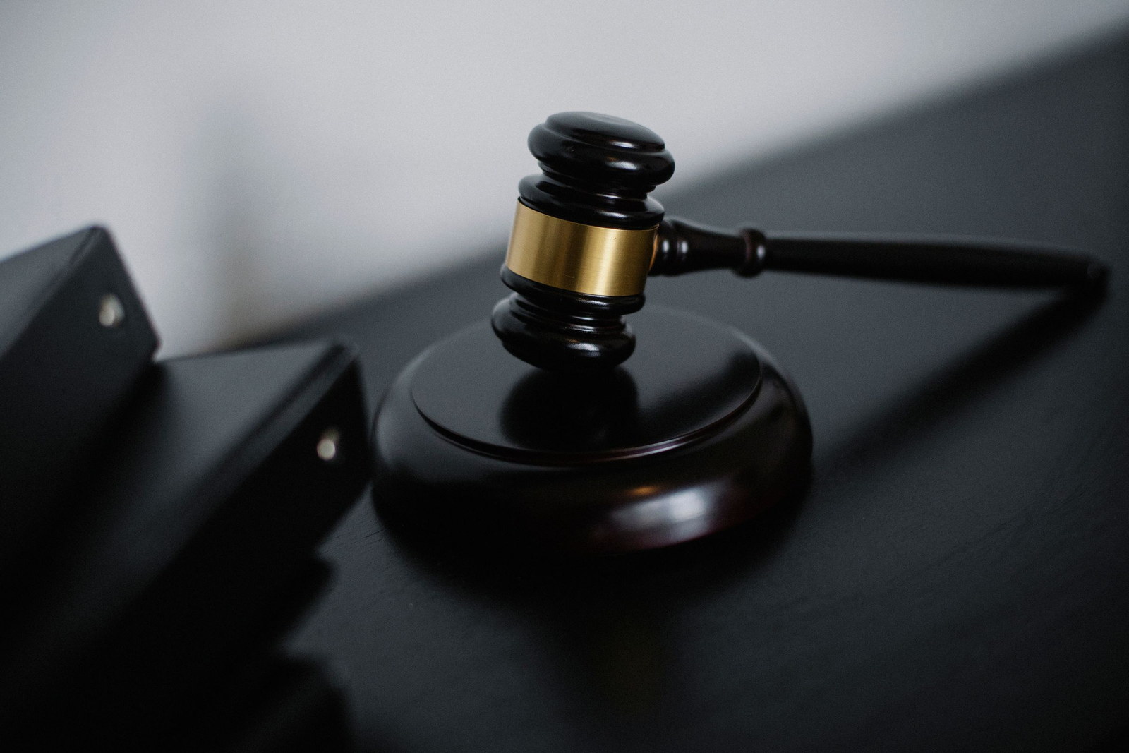A dark wooden auction gavel with a gold band resting on a sounding block